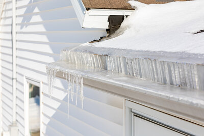 A roof with snow accumulation and ice in the gutters