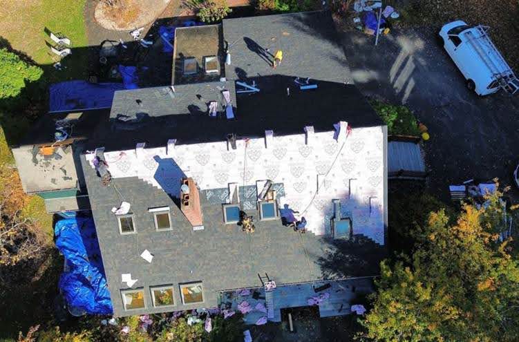 A roofing company in Tewksbury, MA, from Mighty Dog Roofing handling roof work with precision and safety gear on-site.